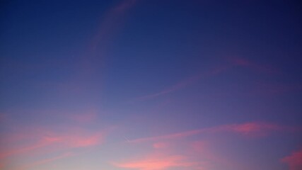 Wall Mural - a calm sunset sky timelapse with soft pink and purple clouds delicately drifting over a clear deep b