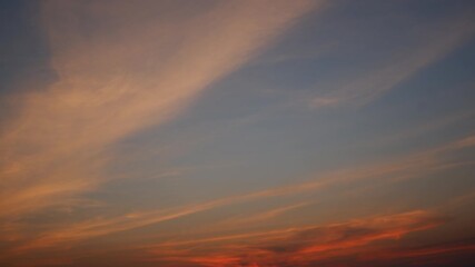 Wall Mural - A fiery sunset sky timelapse with vivid orange and red clouds stretching across a darkening blue backdrop, creating a dramatic and intense evening scene full of warmth and vibrant color. Time lapse.
