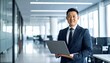 © 순단 강 - A Korean man in a suit holding a laptop computer to the right, with luxury office furniture in the blurred background
