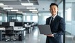 © 순단 강 - A Korean man in a suit holding a laptop computer to the right, with luxury office furniture in the blurred background