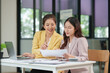 © aekachai - Two Asian businesswomen are sitting in a meeting, planning investment plans, business strategies. On the table are documents and graphs.