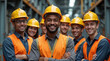 © dubogray1985 - Group of smiling construction workers wearing safety helmets and reflective vests standing together in an industrial environment.