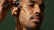 © Yuriy - Young african male applying facial serum for skincare routine on smooth skin