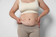 © New Africa - Woman with excessive belly fat on light background, closeup. Overweight problem