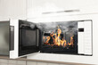 © New Africa - Fire and smoke in microwave oven in kitchen