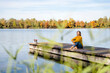 © Westend61 - Woman sitting in front of lake at jetty