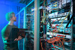 © Westend61 - Technician working in a server room with a laptop and network cables