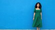 © velikiyzayats - Elegant Young Woman in Green Dress Posing Against Vibrant Blue Background
