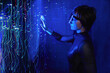 © VISTA by Westend61 - Woman using cyber glasses in a virtual reality simulator with neon lights