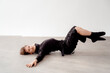 © VISTA by Westend61 - Man in black clothing performing a contemporary dance pose on the floor indoors in Berlin