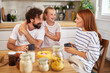 © Stockphotodirectors - A father, daughter, and mother share a cheerful breakfast together at the kitchen table, laughing and enjoying each other's company in a warm, inviting atmosphere.