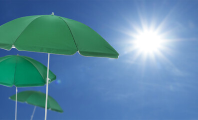 Wall Mural - green beach umbrellas against blue sky on sunny day
