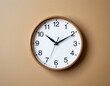 © Anuphong - Simple Wooden Wall Clock with White Face on Beige Background