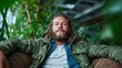 © senadlife - A relaxed man sits comfortably in a cozy chair, surrounded by lush greenery, embodying a moment of peace and connection with nature in an inviting atmosphere.