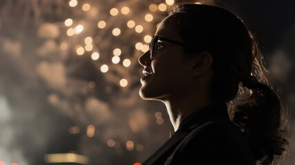 Wall Mural - a woman with glasses looks up at fireworks exploding in the night sky
