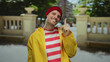 © Krakenimages.com - Young man wearing yellow jacket and red beanie, smiling outdoors in urban street setting, displaying upbeat and cheerful vibe, with blurred cityscape background.