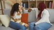 © Krakenimages.com - Two women sitting on a couch in a cozy living room enjoying a friendly conversation together, highlighting warmth and connection in a relaxed indoor setting.