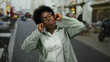 © Krakenimages.com - African american woman wearing glasses makes a playful gesture covering ears and sticking out tongue on a vibrant city street.