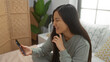 © Krakenimages.com - Woman smiling in bedroom holding phone, relaxing on bed in cozy home interior with natural light, portraying a calm and peaceful indoor setting, emphasizing her happiness.
