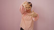© Krakenimages.com - Woman posing playfully against a pink background, featuring a young, attractive, chinese, female with a charming smile and confident demeanor, isolated over a pastel wall.