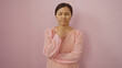 © Krakenimages.com - Woman wearing pink blouse standing against pink wall with thoughtful expression, capturing a serene and beautiful moment of quiet introspection in a minimalist setting.