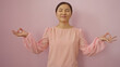 © Krakenimages.com - Woman meditating isolated against pink background with eyes closed exuding calm and peace wearing a light pink blouse in a serene and relaxed pose suggesting mindfulness practice.