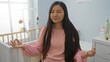 © Krakenimages.com - Woman meditating in a cozy baby room with a cradle, focusing on relaxation and peace, showcasing asian beauty and tranquility in an indoor home setting.