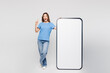 © ViDi Studio - Full body young woman wears blue t-shirt casual clothes big huge blank screen mobile cell phone smartphone with area point index finger up isolated on plain white color background. Lifestyle concept.