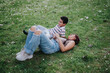 © qunica.com - A joyful scene of a mother and her child enjoying quality time outdoors while lying on a grassy park field, smiling and sharing a laugh. Captures warmth, family bonding, and happiness in nature.