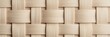 © Tanakrit - Close-up image of a woven natural fiber texture with an interlaced pattern in beige tones.