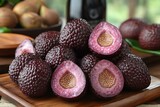Dark red salak fruit sliced open to reveal pink flesh and seed, displayed on wooden tray