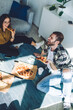 © BullRun - Satisfied friends enjoying pizza while relaxing on floor at home