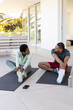 © Wavebreak Media - Stretching Hispanic and African American couple on yoga mats on tiled patio, with smartphone