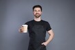 © New Africa - Portrait of smiling barista with paper takeaway cup of hot drink on grey background