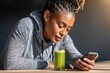 © Svetlana - Black Woman Checks Phone with Green Juice on Wooden Table