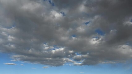 Wall Mural - Timelapse of white to gray summer clouds moving away from the viewer in a bright blue sky
