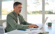 © insta_photos - Busy older mature middle aged man wearing eyeglasses looking at computer technology sitting at table, using laptop hybrid working online, elearning, browsing web, searching online at home.