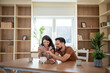 © Migma_Agency - Happy couple saving money together at home putting coins in piggy bank