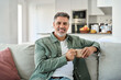 © insta_photos - Portrait of happy middle aged man holding coffee cup relaxing on couch at home. Smiling mature older man drinking tea looking at camera sitting on cozy sofa chilling in modern kitchen living room.
