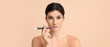 © Pixel-Shot - Beautiful young woman with makeup brush on beige background