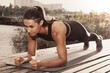 © New Africa - Sporty woman doing plank exercise on wooden pier near river