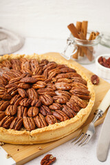 Wall Mural - Wooden board with tasty pecan pie on light background