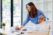© David - Smiling young asian woman sitting at desk working on laptop taking notes in notebook, happy millennial female studying online, watching webinar using computer and writing check list
