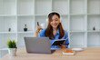 © David - Smiling girl student wear headphone study online with teacher, happy asian woman learn language listen lecture watch webinar write notes look at laptop sit in cafe, distant education