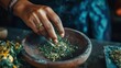 © MohdHanafi - Woman's hand adding dried herbs to a wooden bowl, releasing fragrant smoke.
