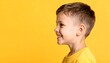 © rifqi - A young boy smiles broadly, his profile highlighted against a vibrant yellow background.