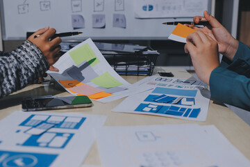 group of young application developers analyzing uxui mobile app templates during a working meeting