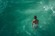 © Usaginikov - Woman Standing Alone in Turquoise Ocean from Behind