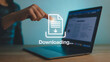 © Moeen - Downloading process on a modern laptop computer represented by a file icon and download arrow, depicting data transfer and online information access.