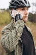 © sav_an_dreas - Young man in casual clothes wearing bike helmet talking on phone outdoors.